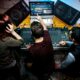 Team managing corporate event audio production using a sound mixing console, speakers, and live monitoring software during an event setup.