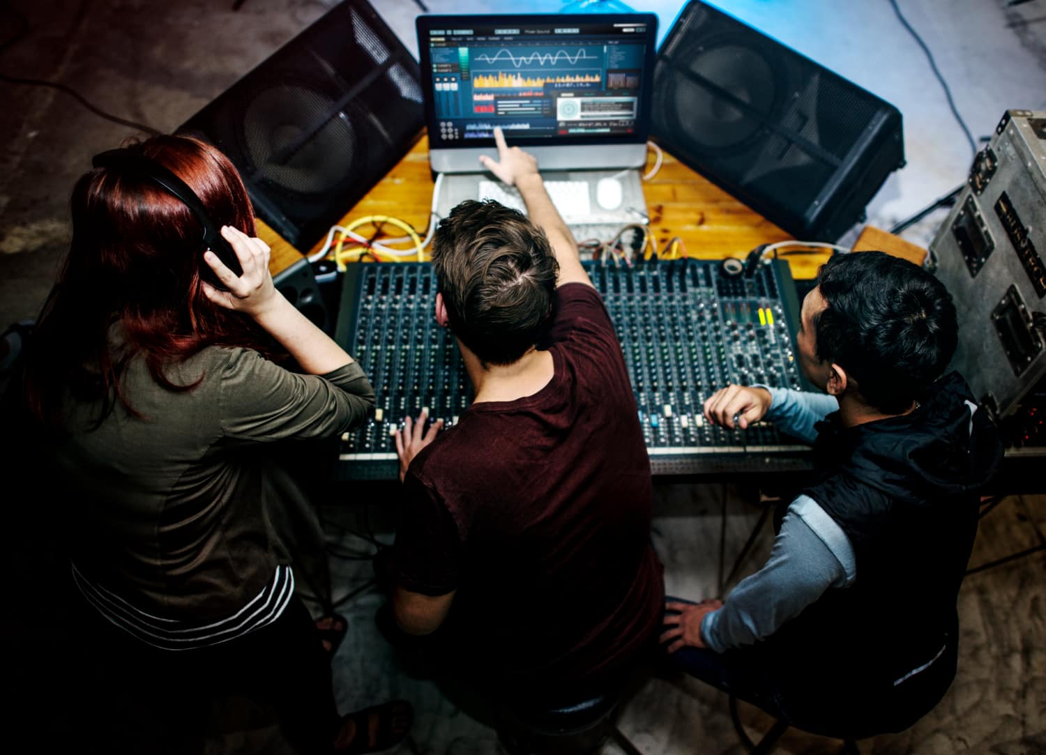 Team managing corporate event audio production using a sound mixing console, speakers, and live monitoring software during an event setup.