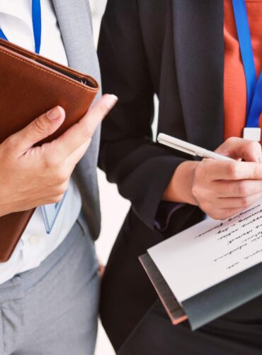 Two corporate event professionals in business attire reviewing documentation.