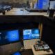 A behind-the-scenes view of a professional hybrid event setup in Dubai, featuring a video switcher and laptops monitoring a live stage presentation.