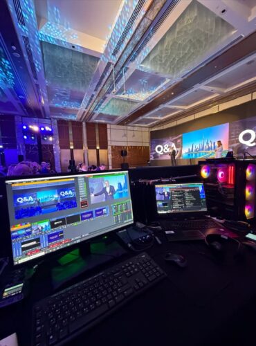 A behind-the-scenes view of a professional event production setup in a large, modern conference hall.